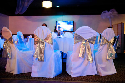White linen and gold bow seat covers at a corporate event
